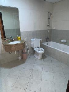 La salle de bains est pourvue d'un lavabo, de toilettes et d'une baignoire. dans l'établissement F30,R4,Single Room on the beach attach bath, à Ajman
