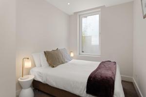 a white bedroom with a bed and a window at Marlin in Melbourne