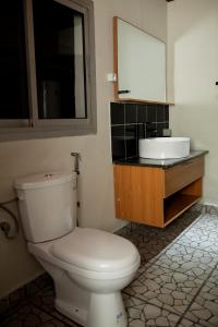 La salle de bains est pourvue de toilettes blanches et d'un lavabo. dans l'établissement KC GuestHouse, à Yaoundé
