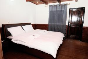 KC GuestHouse في ياوندي: غرفة نوم بسرير وملاءات بيضاء ونافذة