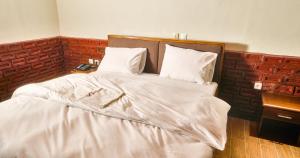 - un lit avec des draps et des oreillers blancs dans l'établissement KC GuestHouse, à Yaoundé