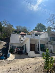 una casa blanca con un coche aparcado en la entrada en Villas las Palmeras Casa Canaria 12 personas, en La Manzanilla