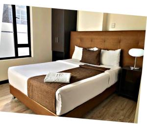 een slaapkamer met een groot bed met een houten hoofdeinde bij Hotel Business Center International in Bogota