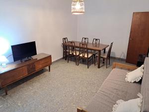 a living room with a dining room table and a television at Belgrano Home - Casa con jardín cerca del Aeropuerto de Ezeiza, hasta 7 pax in Monte Grande