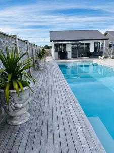 a wooden deck with a swimming pool and a house at Hobbiton Pool House in Matamata