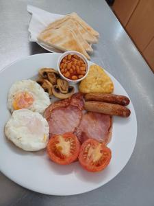 un plato blanco de desayuno con huevos, salchichas y frijoles en The Watling Inn en Nuneaton