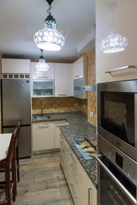 una cocina con armarios blancos y electrodomésticos de acero inoxidable en Casa de la Judería Doña Pilar, en Sevilla