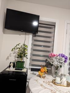 Zimmer mit einem Tisch mit Blumen und einem Flachbild-TV in der Unterkunft Honey Dew in Bowmanville
