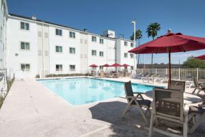- une piscine avec des chaises et un parasol à côté d'un bâtiment dans l'établissement Motel 6-Brownsville, TX, à Brownsville