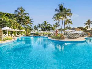 a pool at a resort with chairs and umbrellas at Sofitel Fiji Resort & Spa in Denarau