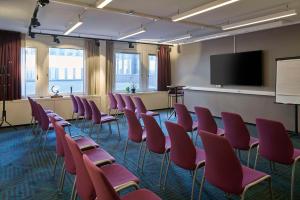 a conference room with red chairs and a flat screen tv at Scandic Europa in Gothenburg