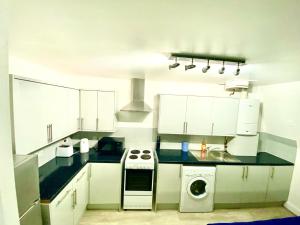 a kitchen with white cabinets and a washer and sink at Cozy One Bedroom Flat Free Car Park In Central London in London