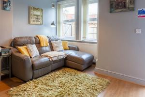 a living room with a leather couch and a rug at Rambler’s Retreat in Dersingham