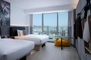 a hotel room with two beds and a large window at Moxy Qiandao Lake in Chun'an
