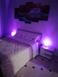 a bedroom with a bed with purple lights on it at Lips House in Gravina in Puglia