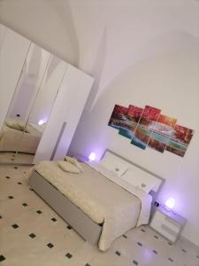 a white bedroom with a bed and two mirrors at Lips House in Gravina in Puglia