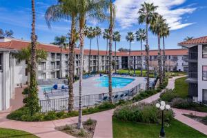 an apartment complex with a pool and palm trees at DoubleTree by Hilton Bakersfield in Bakersfield
