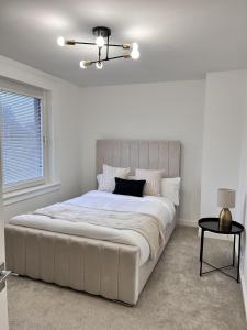 a white bedroom with a large bed and a chandelier at Modern 2 Bedroom Home in Edinburgh Free Parking in Edinburgh