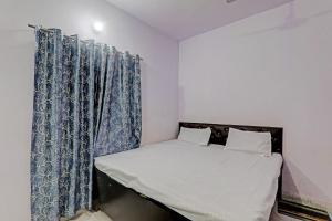 a small bedroom with a bed with blue curtains at Gracious Guest House in Lucknow