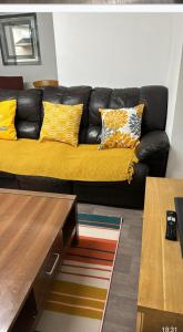 a black couch with yellow pillows in a living room at Northampton town in Kingsthorpe