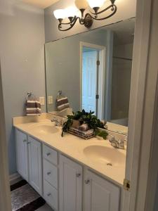 un bagno con due lavandini e un grande specchio di Adorable 3br/2ba W/ Garage 2min walk ECU Health a Greenville
