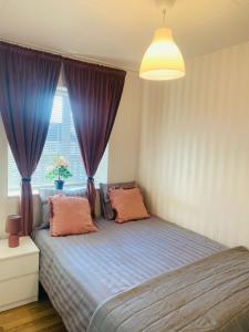 a bedroom with a bed with purple curtains and a window at Noah Longstay Skellefteå in Skellefteå