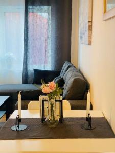 - un salon avec un canapé et un vase avec des fleurs sur une table dans l'établissement Noah Longstay Skellefteå, à Skellefteå