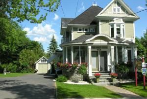a yellow house with flowers in the front yard at BNB Maison Drew in Magog-Orford