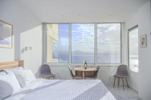a bedroom with a bed and a table and a large window at Ble Property Atlas in Loutraki