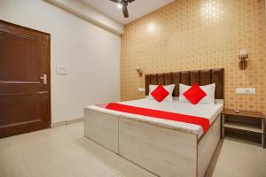 a bedroom with a bed with red pillows on it at Super OYO Hotel Sky Orchid in Ludhiana