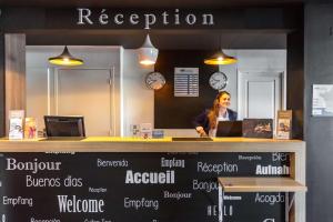 a woman standing at a counter in an office at Brit Hotel Montpellier Parc Expo in Pérols