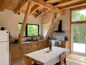 eine Küche mit einem Tisch und eine Küche mit einem Kühlschrank in der Unterkunft Chapella A Frame in LʼAnse-Saint-Jean