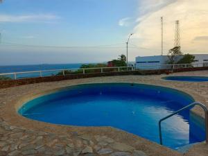 Pampatar的住宿－Playa dorada，一个蓝色的大型游泳池,背景是大海