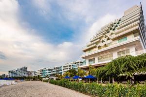 um grande edifício branco com guarda-sóis azuis ao lado de uma praia em Santa Marta Marriott Resort Playa Dormida em Santa Marta