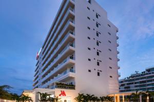 a tall white building with palm trees in front of it at Santa Marta Marriott Resort Playa Dormida in Santa Marta