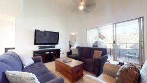 a living room with couches and a flat screen tv at Stylish Home with Mountain Views by Harmony Whistler in Whistler