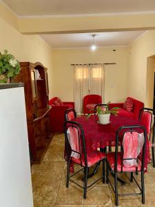 a dining room table with red chairs and a red couch at Las Maravillas del Talampaya II in Villa Unión
