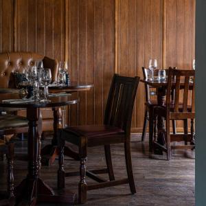 a dining room with tables and chairs with wine glasses at The Three Swallows Cley in Cley next the Sea