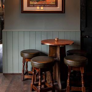 eine Bar mit drei Holzhockern und einem Tisch in der Unterkunft The Three Swallows Cley in Cley next the Sea