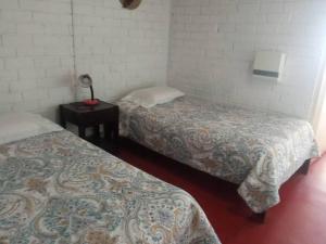 um quarto com duas camas e um candeeiro sobre uma mesa em Beach House SantaElena em Pisco