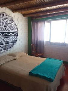 a bedroom with a bed with a green blanket on it at Beach House SantaElena in Pisco