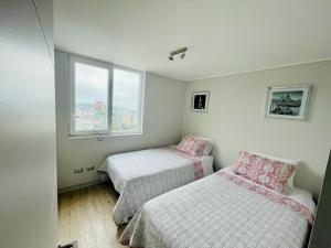 a bedroom with two beds and a window at Departamento 3D-2B vista al mar, 5 personas in Viña del Mar