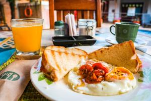 a plate with a sandwich and toast and a glass of beer at Hotel Tierra Roja in Barichara