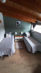 a bedroom with two beds and a table and two windows at Buenavida Guesthouse in Ushuaia