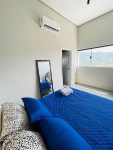 um quarto com uma cama azul e um espelho em APARTAMENTO NOVO A 600 Metros da PRAIA no Guarujá