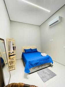 um quarto com uma cama azul num quarto branco em APARTAMENTO NOVO A 600 Metros da PRAIA no Guarujá