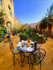 una mesa y sillas con comida en el patio en Riad Fennec Sahara, en Zagora