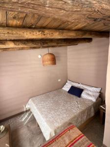 uma cama num quarto com tecto em madeira em La Ventanita de Maima em Maimará