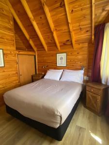 ein Schlafzimmer mit einem Bett in einer Holzhütte in der Unterkunft Cabañas Rukayen in Villa La Angostura