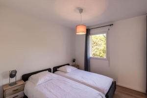 1 dormitorio con cama blanca y ventana en ISLA T3 à 150 m de la plage, en Calvi